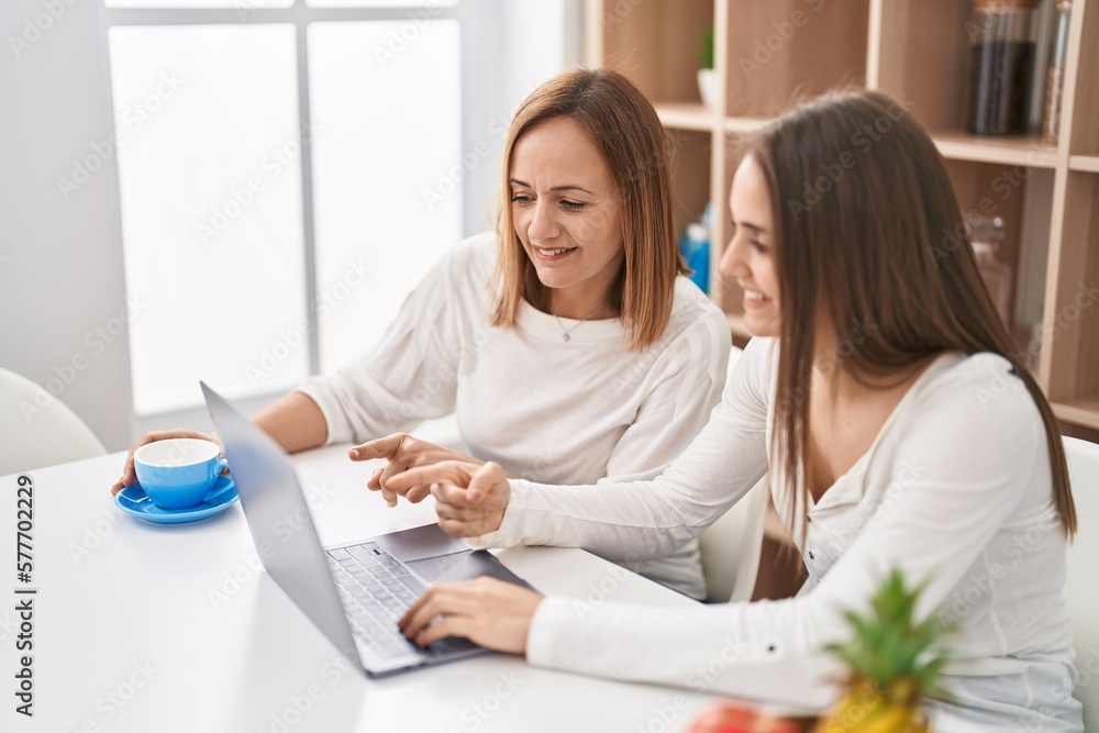 Two women mother and daughter using laptop drinking coffee at home Two women mother and daughter using laptop drinking coffee at home