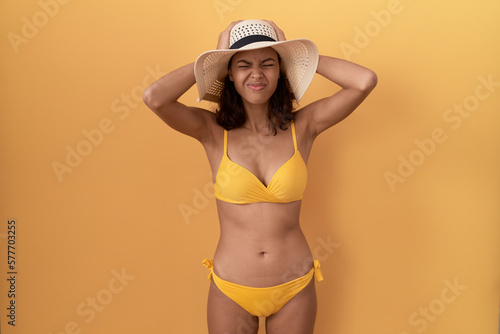 Obraz na plátně Young hispanic woman wearing bikini and summer hat suffering from headache desperate and stressed because pain and migraine