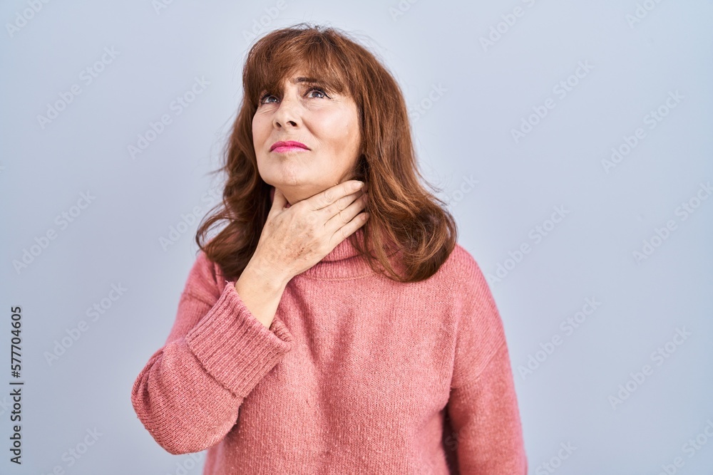 Middle age hispanic woman standing over isolated background touching painful neck, sore throat for flu, clod and infection Middle age hispanic woman standing over isolated background touching painful neck, sore throat for flu, clod and infection