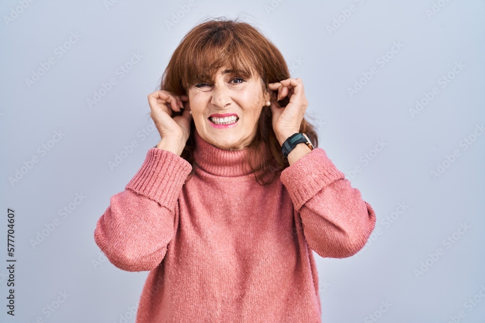 Middle age hispanic woman standing over isolated background covering ears with fingers with annoyed expression for the noise of loud music. deaf concept. Middle age hispanic woman standing over isolated background covering ears with fingers with annoyed expression for the noise of loud music. deaf concept.