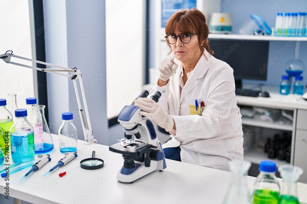 Middle age hispanic woman working at scientist laboratory pointing with finger to the camera and to you, confident gesture looking serious Middle age hispanic woman working at scientist laboratory pointing with finger to the camera and to you, confident gesture looking serious