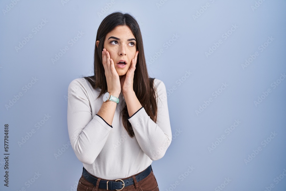 Young brunette woman standing over blue background tired hands covering face, depression and sadness, upset and irritated for problem Young brunette woman standing over blue background tired hands covering face, depression and sadness, upset and irritated for problem