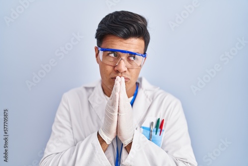 Hispanic man working as scientist begging and praying with hands together with hope expression on face very emotional and worried. begging.