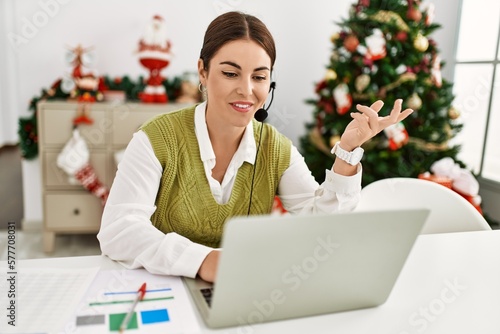 Young beautiful hispanic woman call center agent sitting by christmas tree speaking at home © Krakenimages.com