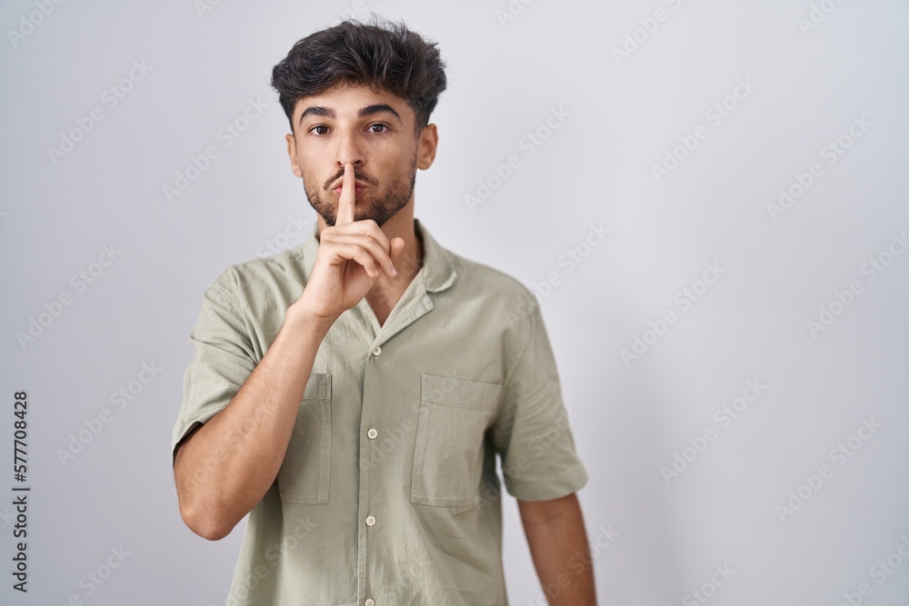 Arab man with beard standing over white background asking to be quiet with finger on lips. silence and secret concept. Arab man with beard standing over white background asking to be quiet with finger on lips. silence and secret concept.