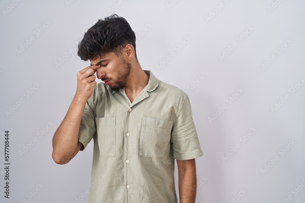 Arab man with beard standing over white background tired rubbing nose and eyes feeling fatigue and headache. stress and frustration concept. Arab man with beard standing over white background tired rubbing nose and eyes feeling fatigue and headache. stress and frustration concept.
