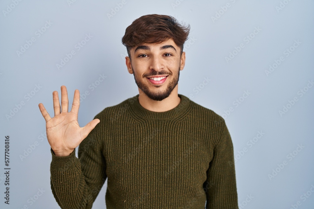 Arab man with beard standing over blue background showing and pointing up with fingers number five while smiling confident and happy. Arab man with beard standing over blue background showing and pointing up with fingers number five while smiling confident and happy.