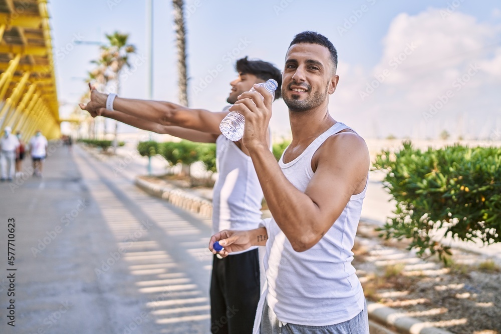 Two hispanic men sporty couple smiling confident drinking water at street Two hispanic men sporty couple smiling confident drinking water at street