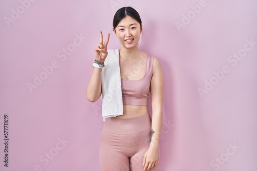 Chinese young woman wearing sportswear and towel showing and pointing up with fingers number two while smiling confident and happy.