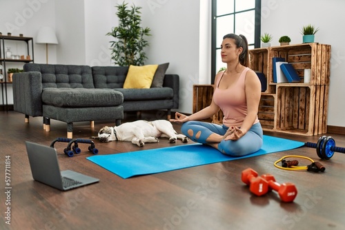 Young woman having online yoga class at home