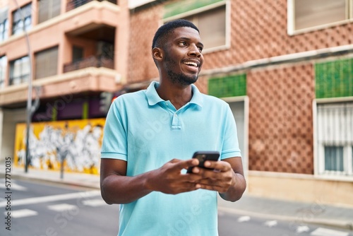 Young african american man smiling confident using smartphone at street