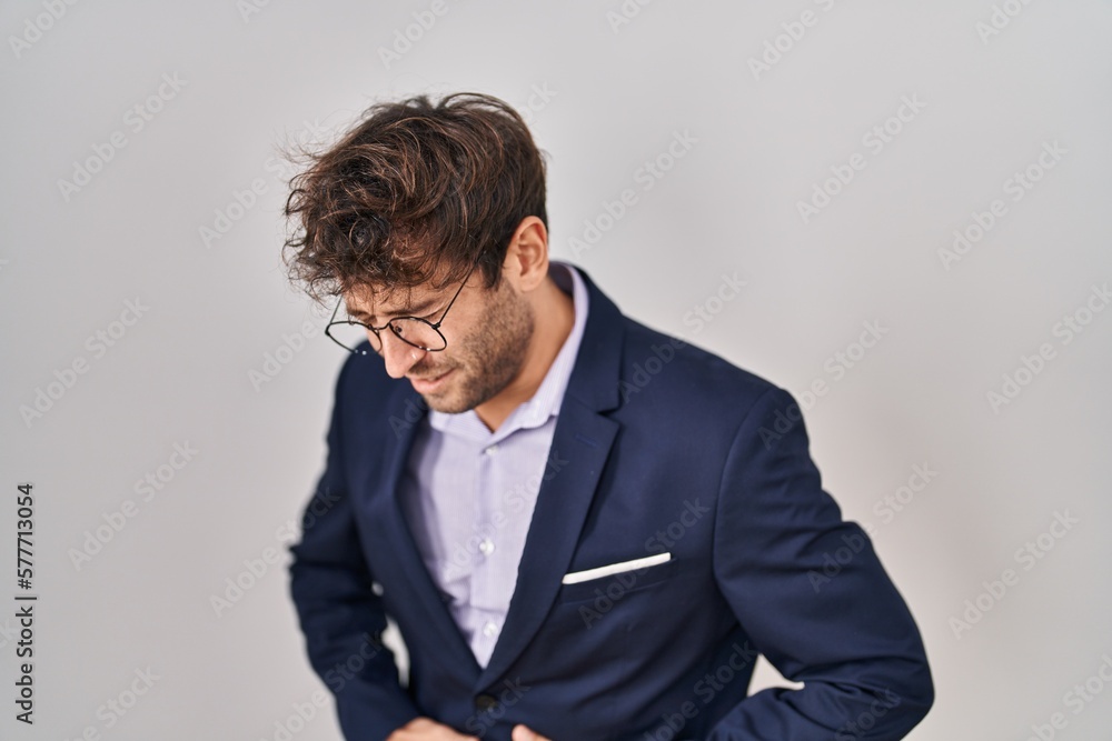 Hispanic business man wearing glasses with hand on stomach because indigestion, painful illness feeling unwell. ache concept. Hispanic business man wearing glasses with hand on stomach because indigestion, painful illness feeling unwell. ache concept.