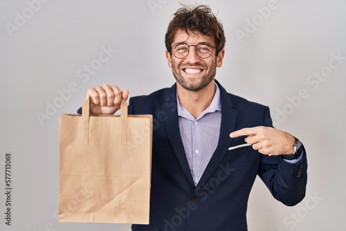 Hispanic business man holding delivery bag pointing finger to one self smiling happy and proud