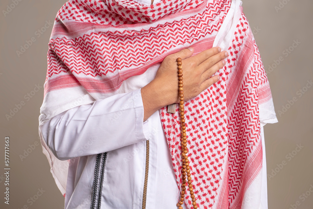 Selective focus body image of muslim man holding prayer beads and wearing kufiya
