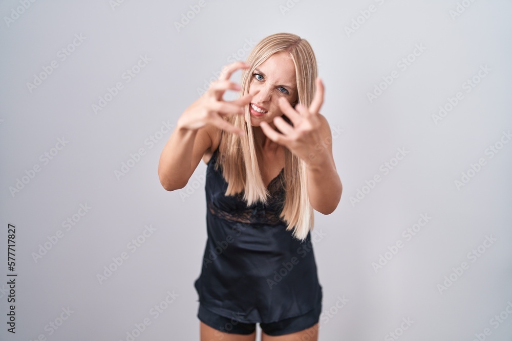 Young caucasian woman wearing nightgown shouting frustrated with rage, hands trying to strangle, yelling mad Young caucasian woman wearing nightgown shouting frustrated with rage, hands trying to strangle, yelling mad