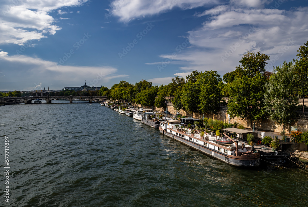 River Seine In Paris, France With Promenade And Anchored Houseboats