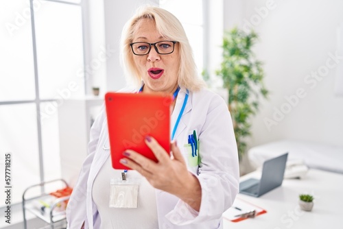 Middle age caucasian woman working on online appointment scared and amazed with open mouth for surprise, disbelief face