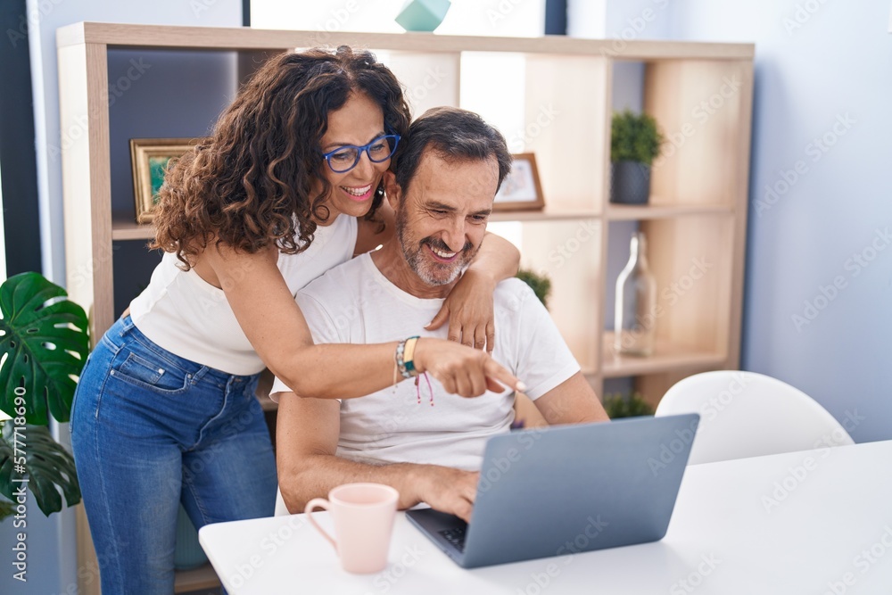 Man and woman couple hugging each other using laptop at home Man and woman couple hugging each other using laptop at home