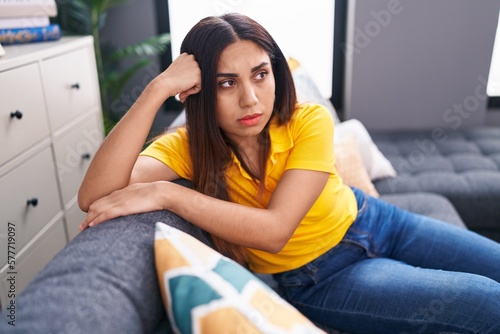 Young beautiful arab woman sitting on sofa with serious expression at home