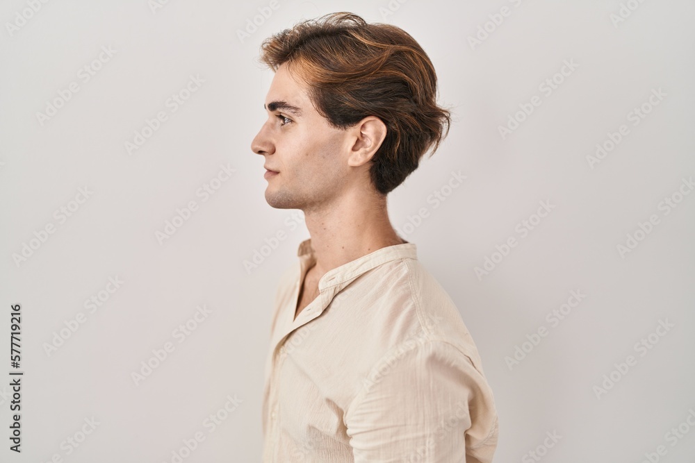 Young man standing over isolated background looking to side, relax profile pose with natural face and confident smile. Young man standing over isolated background looking to side, relax profile pose with natural face and confident smile.