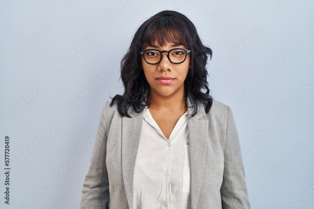 Hispanic woman standing over isolated background relaxed with serious expression on face. simple and natural looking at the camera.