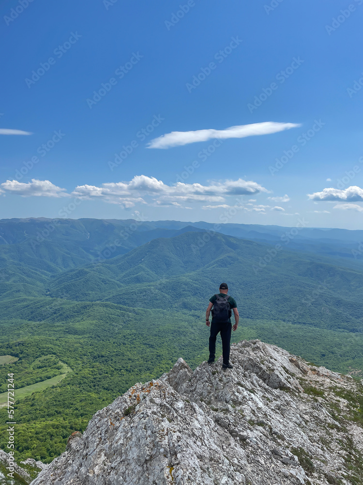 a man stands on a mountain and looks into the distance under a blue sky hiking journey