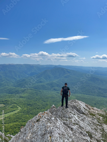 a man stands on a mountain and looks into the distance under a blue sky hiking journey