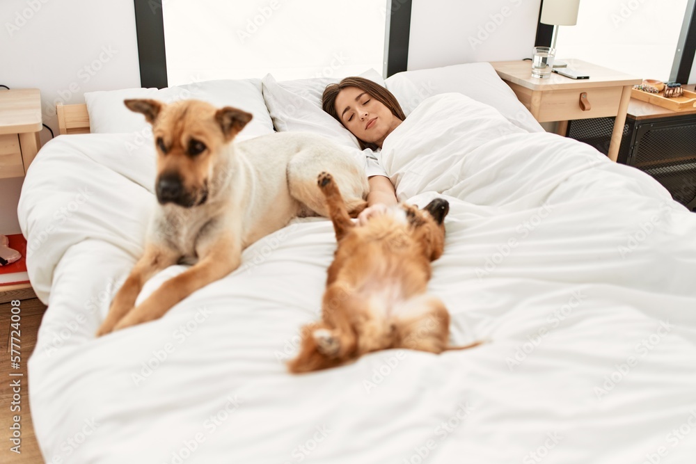 Obraz premium Young hispanic woman sleeping lying on bed with dogs at bedroom
