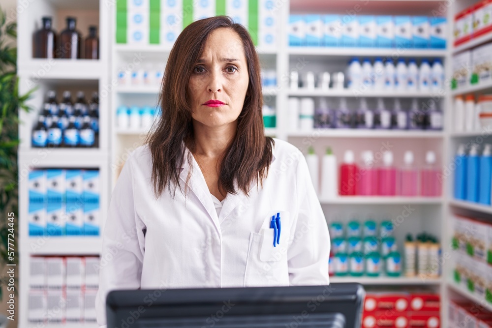 Middle age brunette woman working at pharmacy drugstore skeptic and nervous, frowning upset because of problem. negative person.