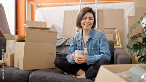 Young caucasian woman sitting on the sofa drinking a cup of coffee at new home © Krakenimages.com