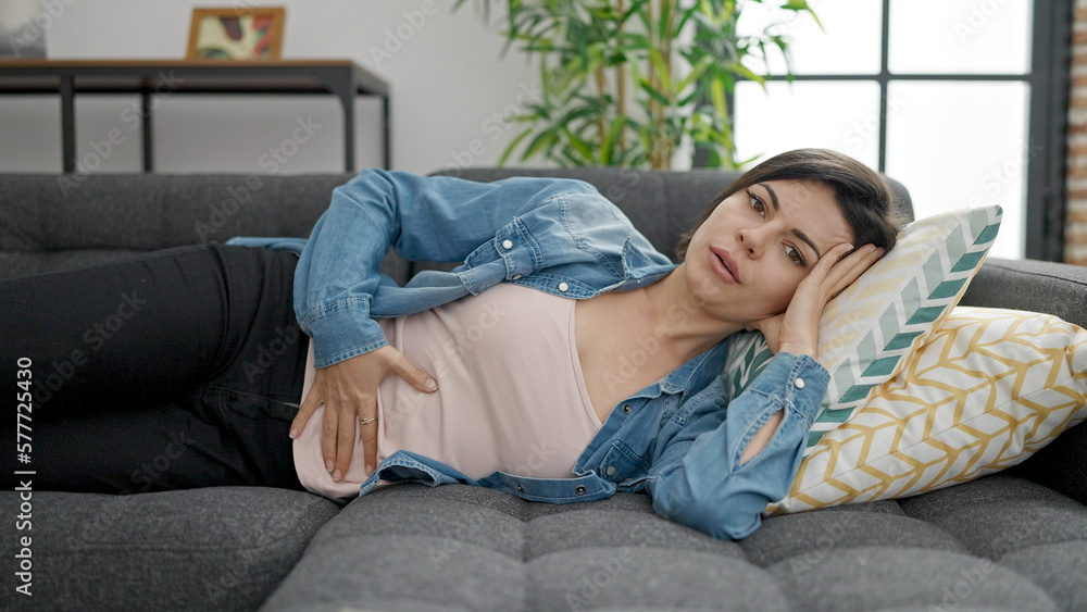 Young caucasian woman suffering for stomach ache lying on sofa at home Young caucasian woman suffering for stomach ache lying on sofa at home