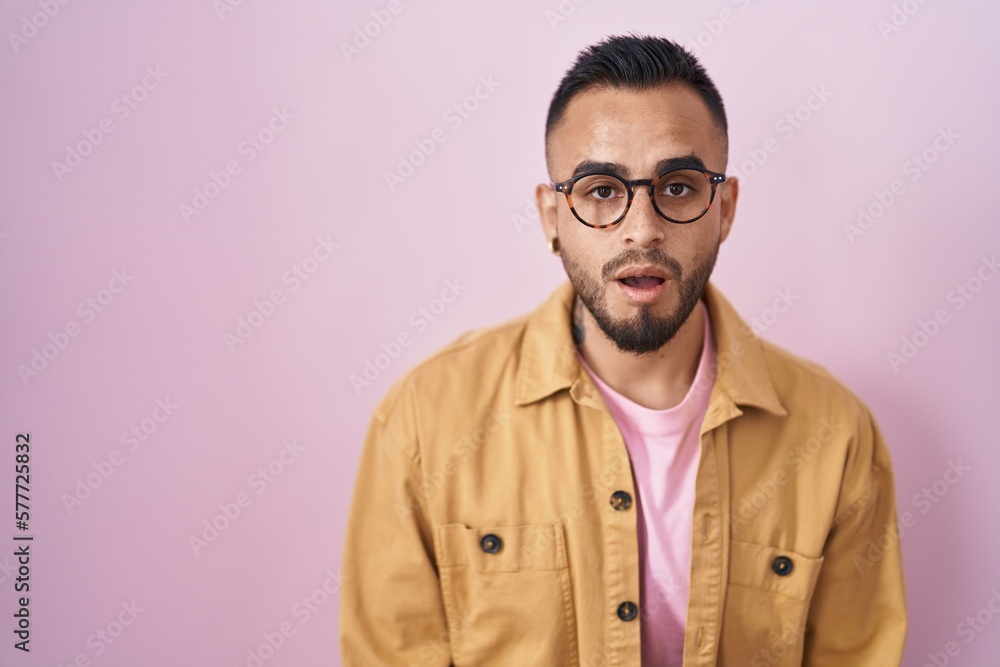 Young hispanic man standing over pink background afraid and shocked with surprise expression, fear and excited face. Young hispanic man standing over pink background afraid and shocked with surprise expression, fear and excited face.
