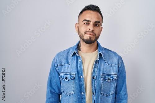 Young hispanic man standing over isolated background relaxed with serious expression on face. simple and natural looking at the camera. © Krakenimages.com