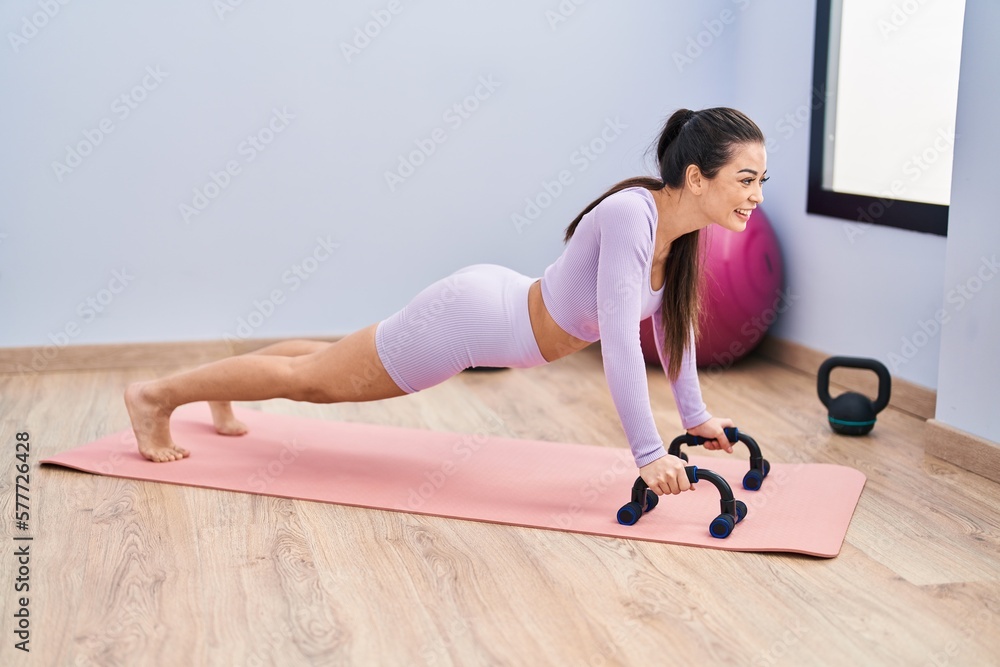 Young beautiful hispanic woman smiling confident training push up at sport center