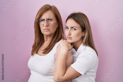 Hispanic mother and daughter wearing casual white t shirt skeptic and nervous, frowning upset because of problem. negative person.