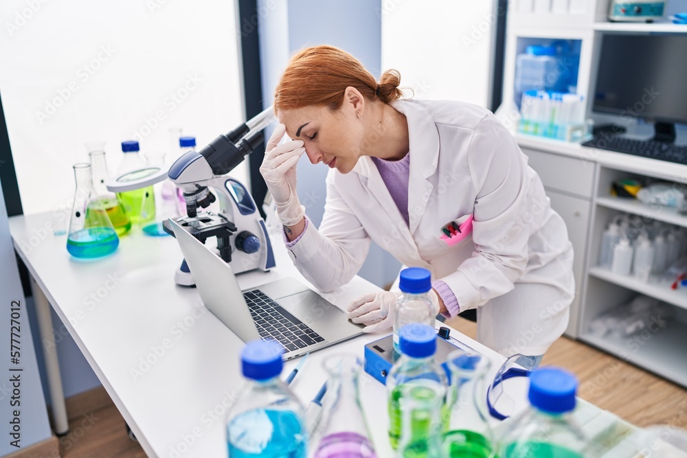 Young caucasian woman scientist stressed using laptop working at laboratory Young caucasian woman scientist stressed using laptop working at laboratory