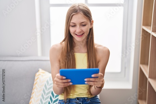Young caucasian woman using touchpad sitting on sofa at home