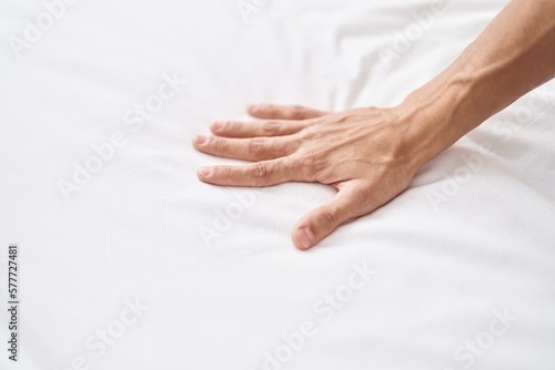 Young hispanic man stretch the sheet at bedroom