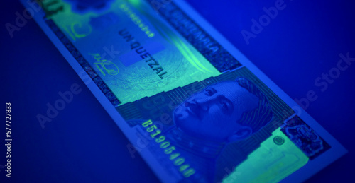 Guatemalan banknotes under UV light. Checking for counterfeit money. Close-up Guatemala quetzales. UV light banknote detector. Fake money testing