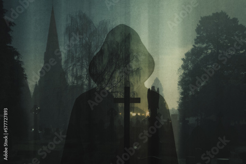 A spooky double of exposure of a mysterious silhouette of a hooded figure. With a scary graveyard and church in the background. On an eerie foggy winters night.