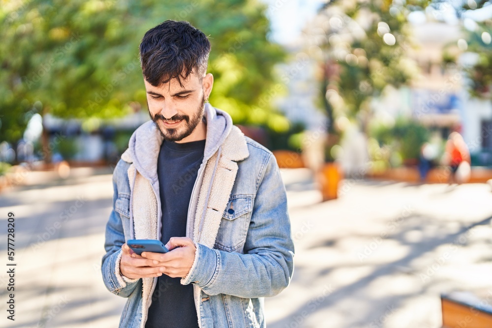 Fototapeta premium Young hispanic man smiling confident using smartphone at park