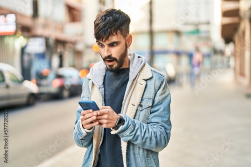 Принти на полотні Young hispanic man using smartphone with surprise expression at street