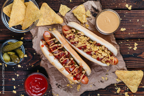 фотографія hot dogs with pickles, bacon, and nachos on a dark wooden background selective f