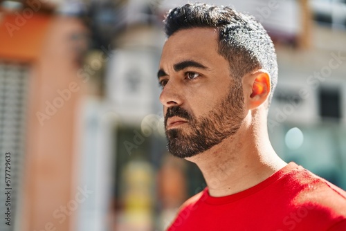 Young hispanic man with relaxed expression standing at street