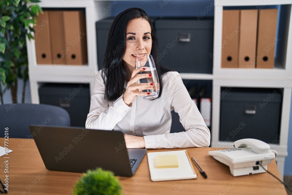 Young caucasian woman business worker using laptop drinking glass of water at office Young caucasian woman business worker using laptop drinking glass of water at office