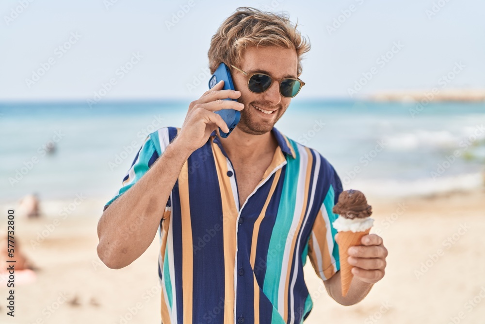 Young man tourist talking on the smartphone eating ice cream at seaside