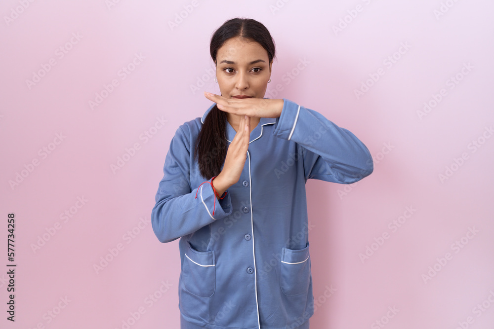 Young arab woman wearing blue pajama doing time out gesture with hands, frustrated and serious face Young arab woman wearing blue pajama doing time out gesture with hands, frustrated and serious face