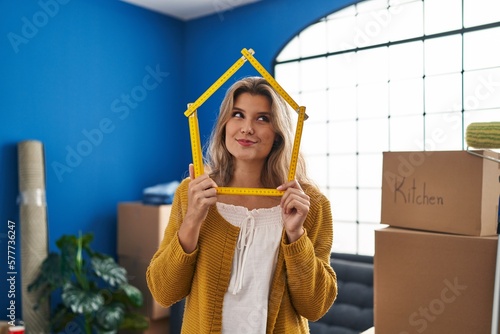 Young woman standing at new home smiling looking to the side and staring away thinking. photo