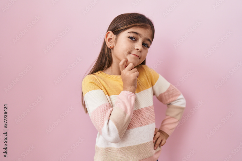 Little hispanic girl wearing sweater over pink background smiling looking confident at the camera with crossed arms and hand on chin. thinking positive. Little hispanic girl wearing sweater over pink background smiling looking confident at the camera with crossed arms and hand on chin. thinking positive.