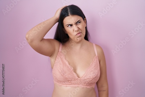 Young hispanic woman wearing pink bra confuse and wondering about question. uncertain with doubt, thinking with hand on head. pensive concept.